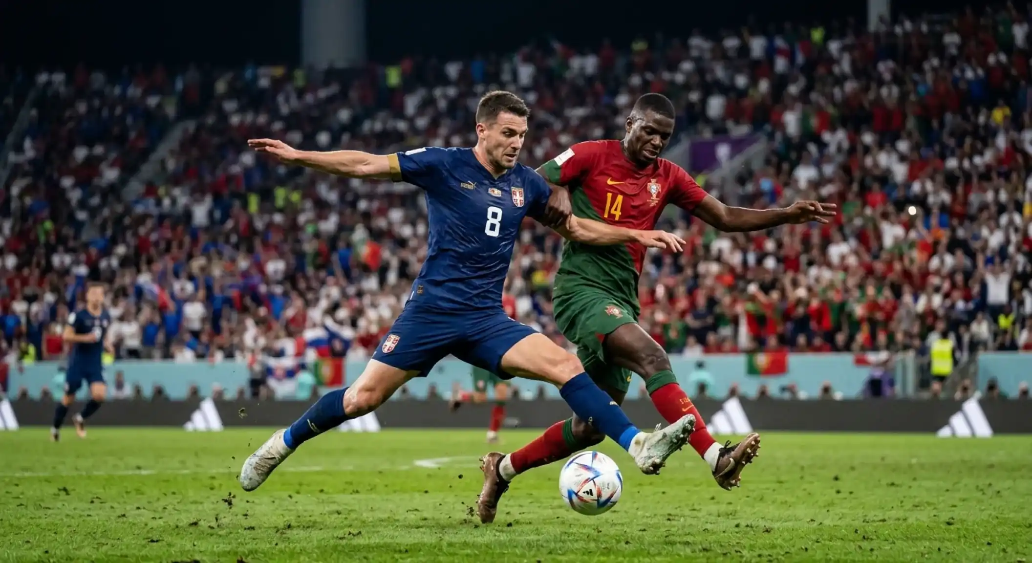 Two footballers in blue and in red-and-green kits contesting the ball under floodlights at a packed stadium, tense knockout atmosphere