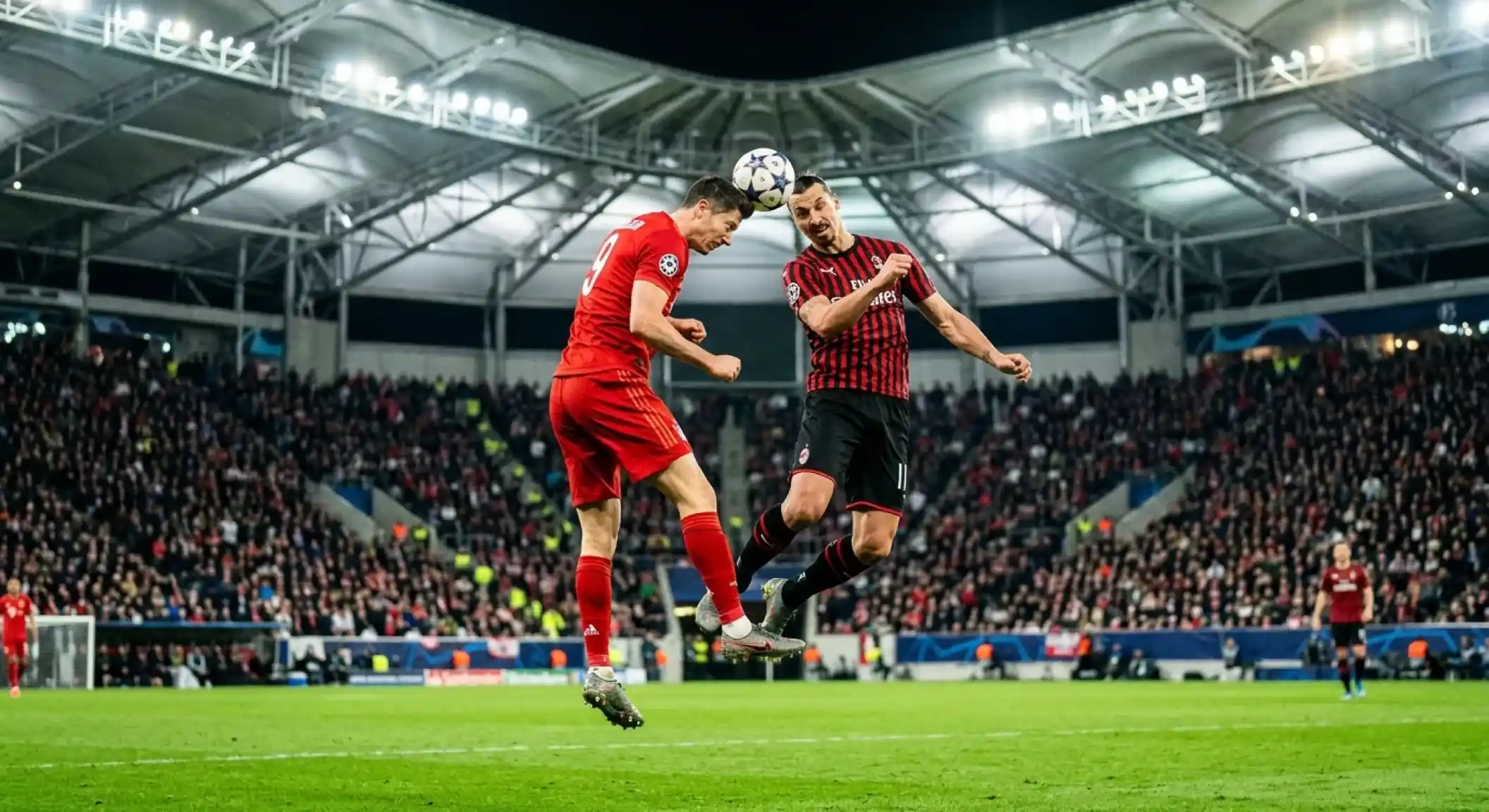 Footballers in red and in red-and-black kits competing for a header inside a modern covered stadium, floodlit turf, knockout tension